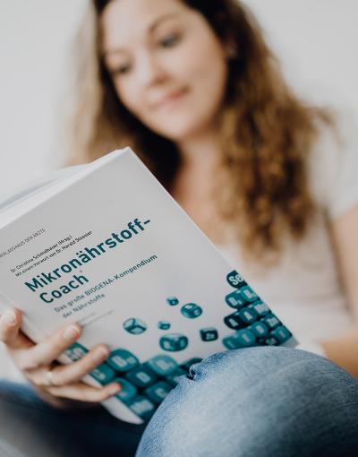 Frau liest in Biogena Mikronährstoffhandbuch nach